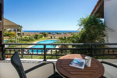 a table and chairs on a balcony with a view of a pool at Villa Seashell in Pefki Rhodes
