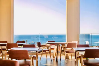 a room with tables and chairs and a large window at Este Elegant Suites & Villas in Kiotari