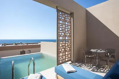 a room with a swimming pool and a table and chairs at Este Elegant Suites & Villas in Kiotari