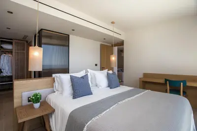 a bedroom with a large white bed with blue pillows at Este Elegant Suites & Villas in Kiotari