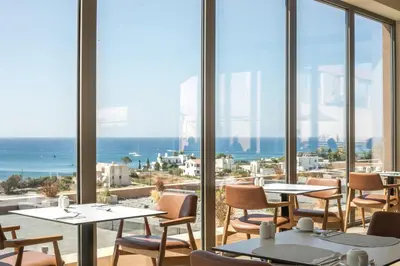 a restaurant with tables and chairs and a view of the ocean at Este Elegant Suites & Villas in Kiotari
