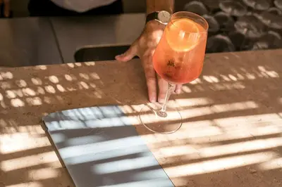 a person holding a drink on a table at Este Elegant Suites & Villas in Kiotari