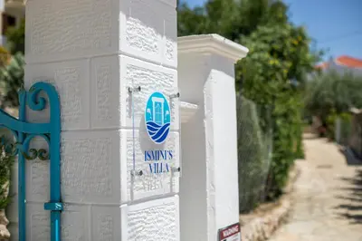 a white pillar with a sign on it next to a fence at Isminis Villa in Halki