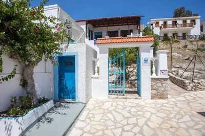 a white building with a blue door and a tree at Isminis Villa in Halki