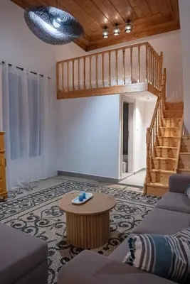 a living room with a staircase and a table at Diolanth traditional house in Koskinou