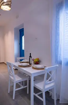 a white table with two chairs and a bottle of wine at Diolanth traditional house in Koskinou