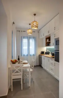 a white kitchen with a white table and chairs at Diolanth traditional house in Koskinou