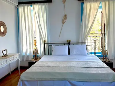 a bedroom with a bed with blue walls and a window at Maestro apartment Chalki in Halki