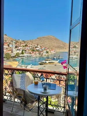 a balcony with a table and a view of a harbor at Maestro apartment Chalki in Halki
