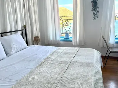 a bedroom with a white bed and a window at Maestro apartment Chalki in Halki