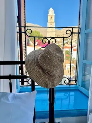 a straw hat sitting on a balcony with a window at Maestro apartment Chalki in Halki