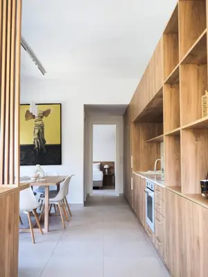 a kitchen with wooden cabinets and a dining table at Trinity Urban Residences Plumeria in Rhodes Town