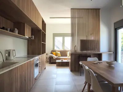 a kitchen with wooden cabinets and a dining table at Trinity Urban Residences Plumeria in Rhodes Town