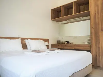 a bedroom with a large white bed with wooden cabinets at Trinity Urban Residences Plumeria in Rhodes Town