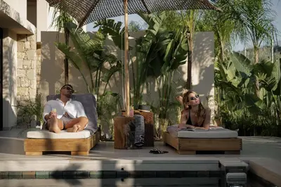 a man and woman sitting in chairs next to a swimming pool at Terra Mare Villas in Ialyssos
