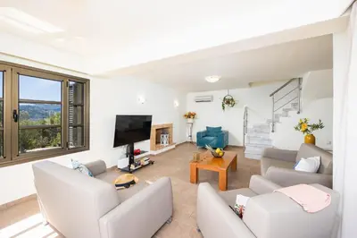 a living room with white furniture and a flat screen tv at Villa Elena in Kalathos