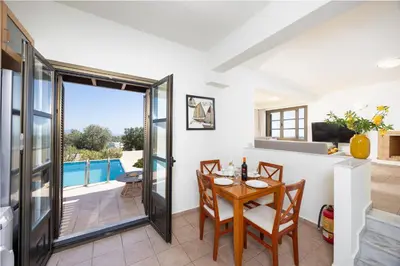 a dining room with a table and chairs and a balcony at Villa Elena in Kalathos