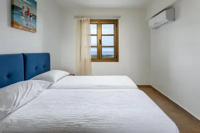 a white bed in a room with a window at Villa Daphne in Kalathos