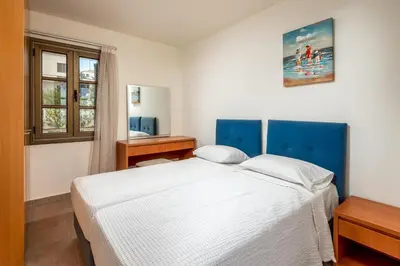 a bedroom with a white bed and a window at Villa Daphne in Kalathos