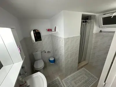 a white bathroom with a toilet and a shower at Giulia's Beach House in Rhodes Town