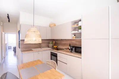 a kitchen with white cabinets and a wooden table at FeWo Traum auf Rhodos in Rhodes Town