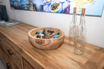 a wooden bowl on top of a wooden table with two bottles at FeWo Traum auf Rhodos in Rhodes Town