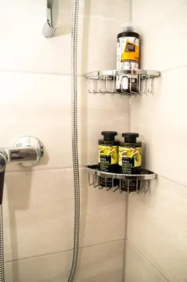 a bathroom with a shower stall with two shelves with toiletries at FeWo Traum auf Rhodos in Rhodes Town