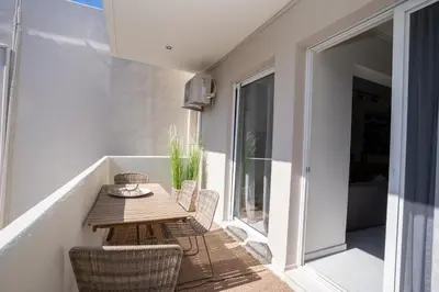 a small balcony with a wooden table and chairs at FeWo Traum auf Rhodos in Rhodes Town