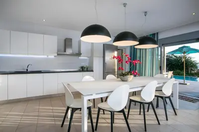 a kitchen and dining room with a white table and chairs at Villa Lily in Pefki Rhodes