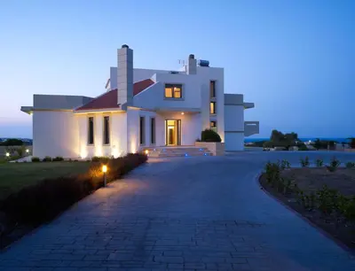 a large white house at night with a driveway at Villa Artemis in Koskinou