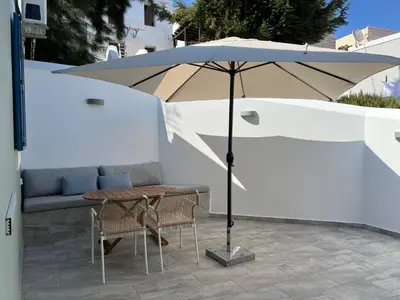 an umbrella on a patio with a table and chairs at FEDON Guesthouse in Halki
