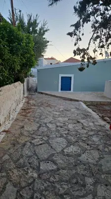 a stone walkway in front of a white building at FEDON Guesthouse in Halki