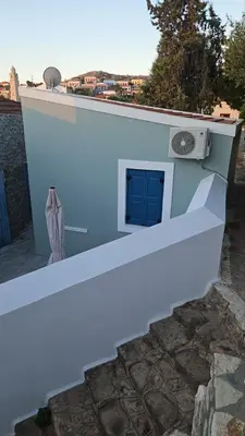 a white building with a blue door and a window at FEDON Guesthouse in Halki