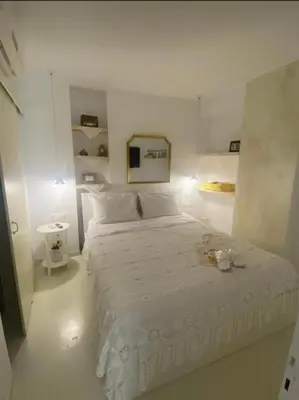 a white bedroom with a bed and a mirror at Álas Holiday Home in Archangelos