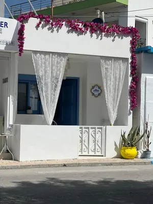 a white house with flowers on a porch at Álas Holiday Home in Archangelos