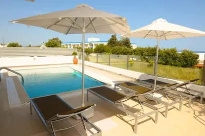 a group of chairs and umbrellas next to a swimming pool at Gennadi Aegean Horizon Villas in Gennadi