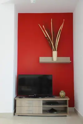 a flat screen tv in a room with a red wall at Gennadi Aegean Horizon Villas in Gennadi