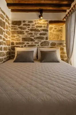 a large bed in a room with a stone wall at Apollon Traditional House in Apóllona