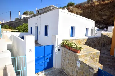a white house with a blue door and a stone wall at Athina's house in Archangelos
