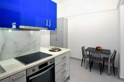 a kitchen with blue cabinets and a table with chairs at Athina's house in Archangelos