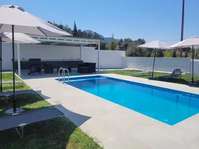 a swimming pool with an umbrella and a patio at Villa Maritsá in Pastida