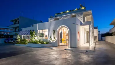 a white house with a lit up facade at night at Patricia Suites in Faliraki