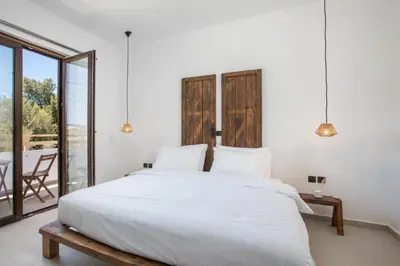 a bedroom with a large white bed and a balcony at Zaia Suites & Living , Suite N6 , sea side view in Gennadi