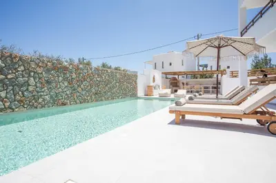 a pool with chaise lounge chairs next to a villa at Zaia Suites & Living , Suite N6 , sea side view in Gennadi