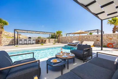 a patio with chairs and a table and a pool at Villa 13 Zendo in Kolimbia