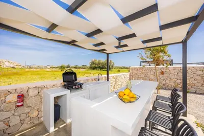 a patio with a table and chairs and a grill at Villa 12 Chado in Kolimbia