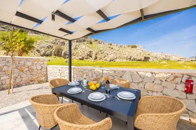a table with chairs and an umbrella on a patio at Villa 10 Hozan in Kolimbia