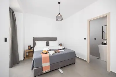 a bedroom with a bed and a bathroom with a sink at Villa 10 Hozan in Kolimbia