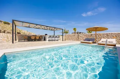 a pool with a table and chairs and an umbrella at Villa 10 Hozan in Kolimbia
