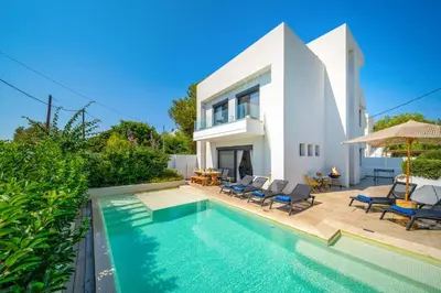 a villa with a swimming pool in front of a house at Villa Thalassa Ixia by Villa Plus in Ialyssos